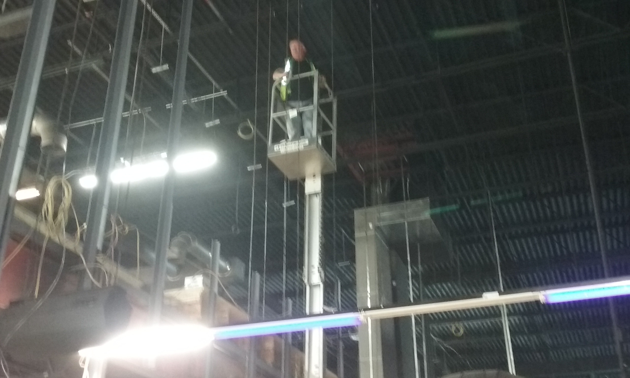 Worker on aerial lift platform at night — commercial AV installation