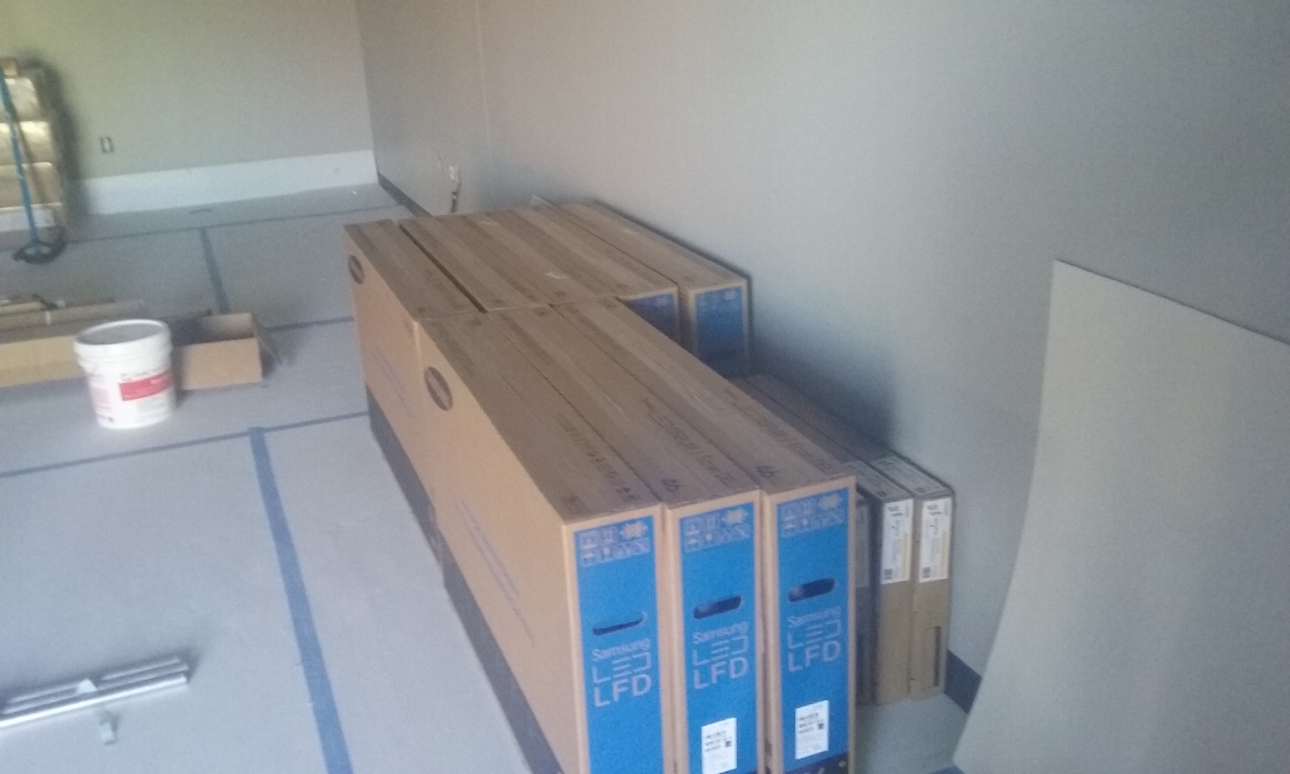 Flooring samples stacked in empty room — pre-install client walkthrough