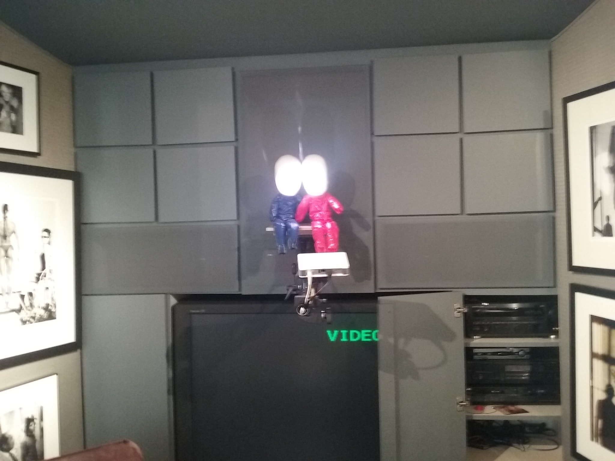 Neon figures on illuminated display shelf — decorative AV installation