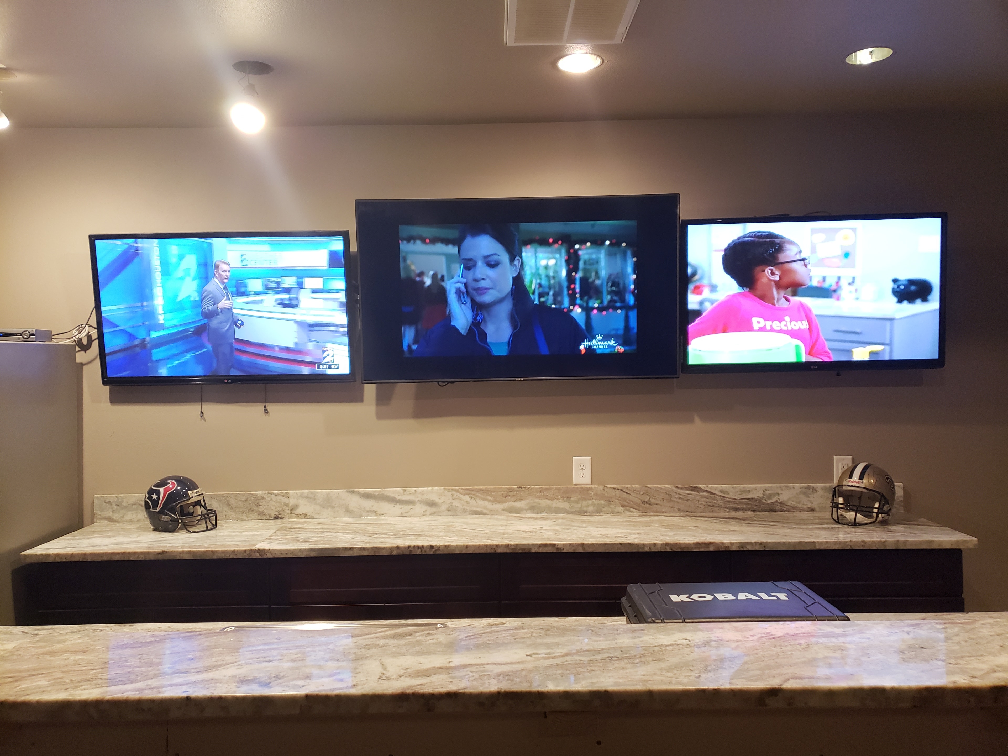 Three televisions displaying content on custom wall mount
