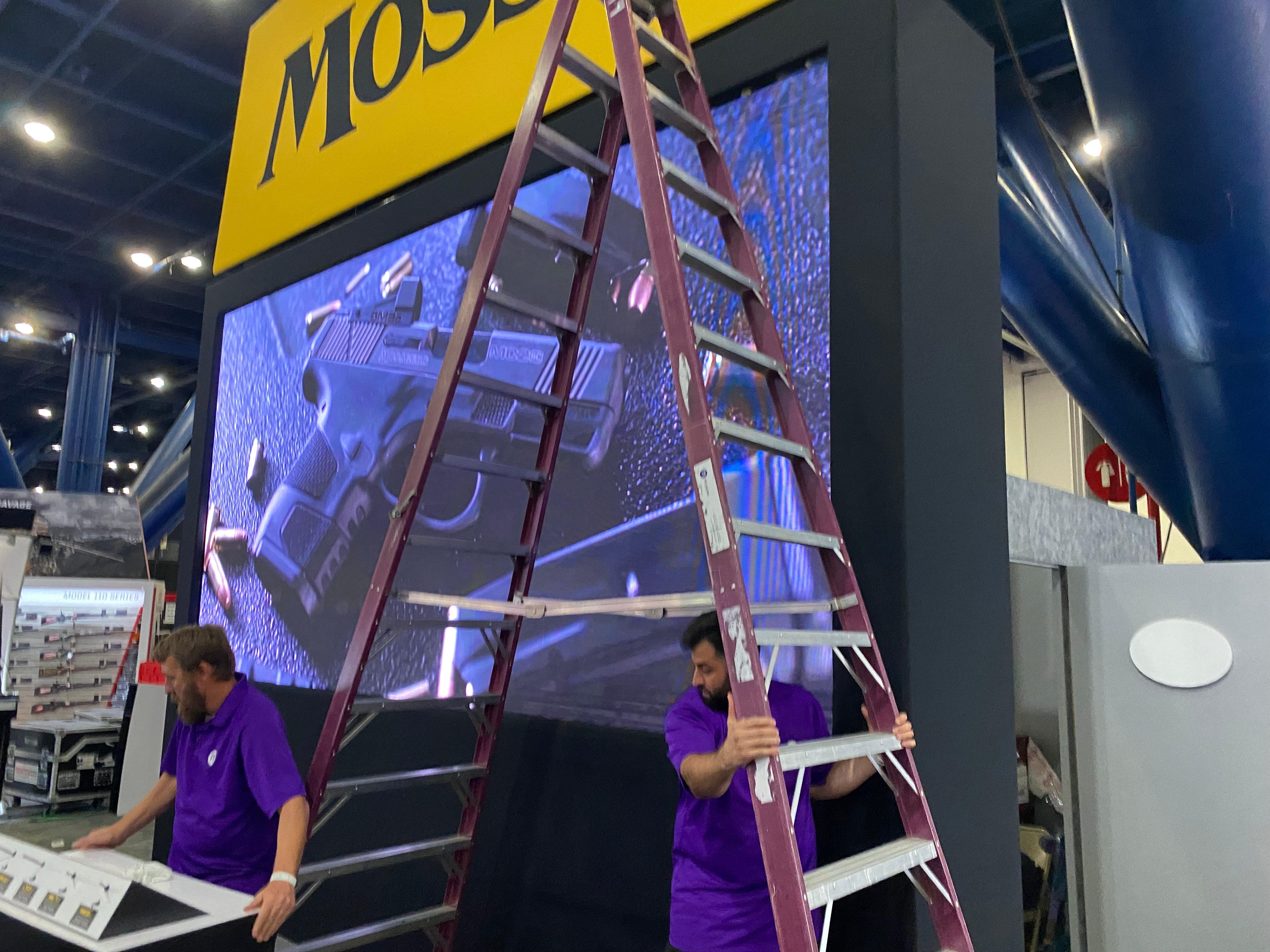 Workers installing large digital display screen at commercial site