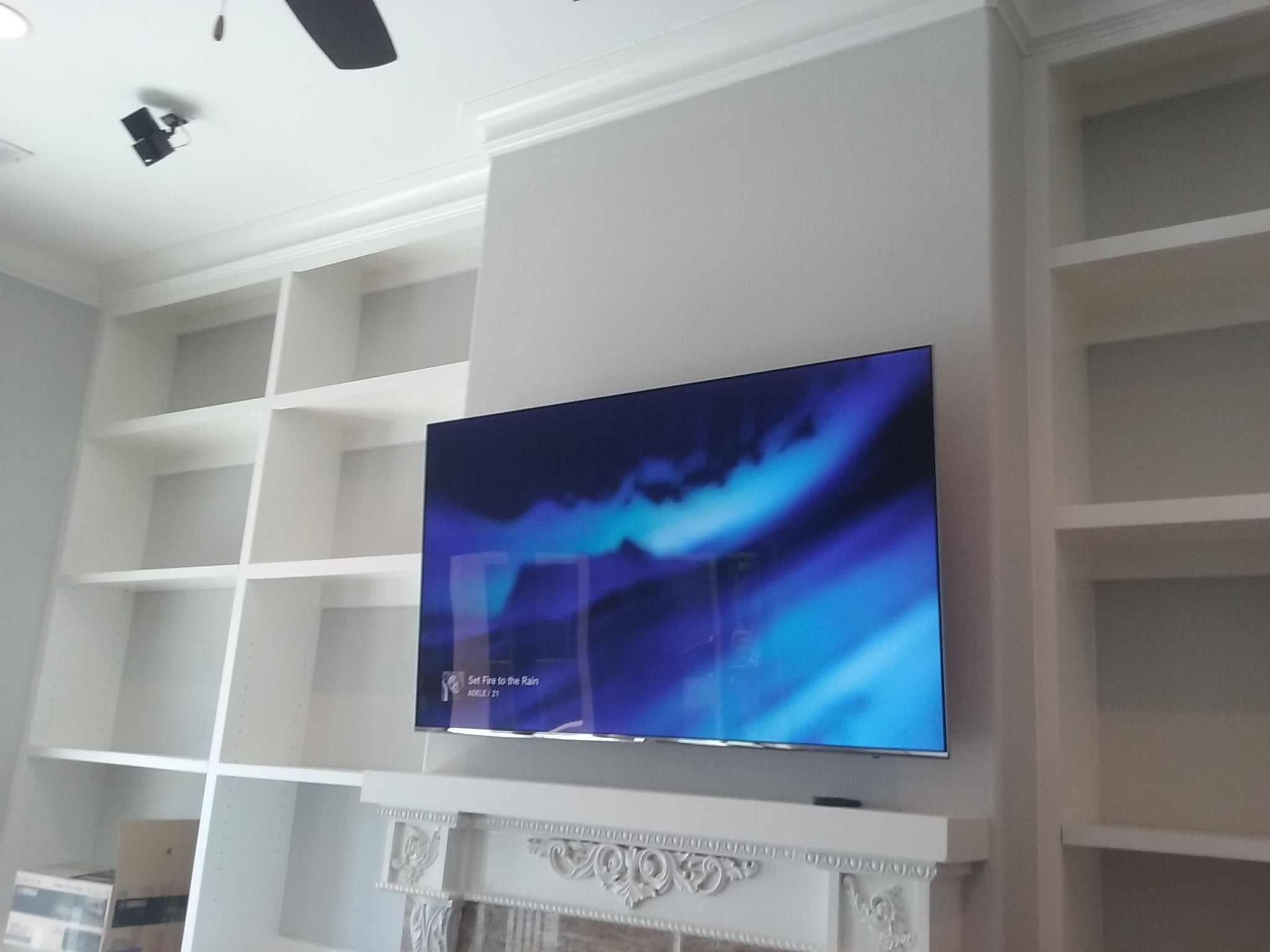 Flat screen TV mounted on white shelving unit — residential audio/video install